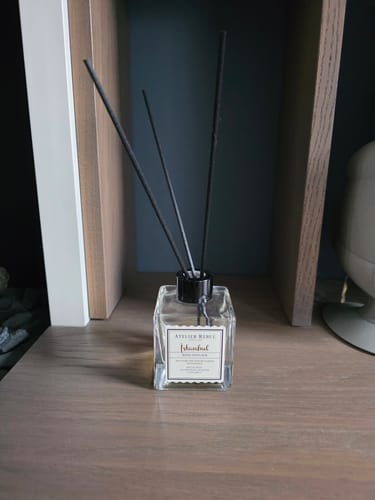 De Istanbul geurstokjes van een recensent in het vierkante flesje op een houten plank.