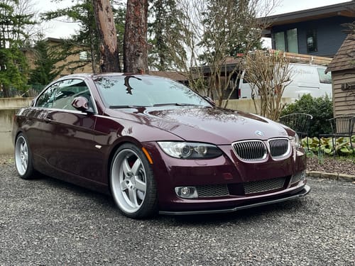 Customer's dark red BMW coupe with wheel spacers installed, viewed from the front, showing a wider stance.