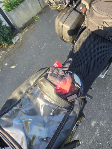 Close-up of a reviewer's black mesh Wind Rider Seat Cover fitted on a motorcycle passenger seat.