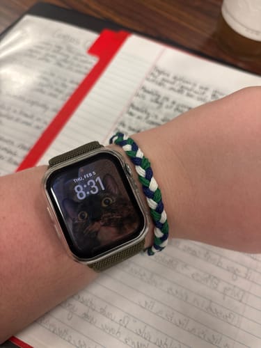 Customer wearing the woven DAVID Bracelet in blue, green, and white on their wrist next to a watch.