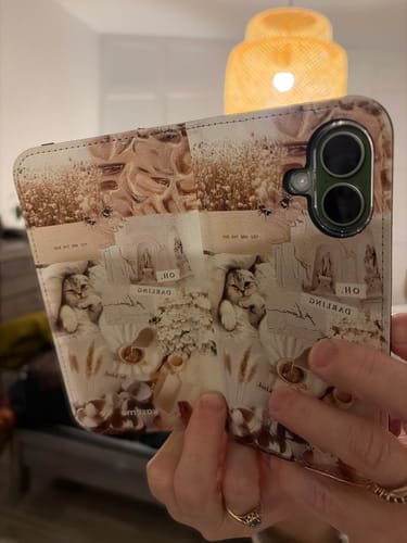 A customer holds the open Darlin' Folio Case, showing its vintage cat pattern and card slots inside.