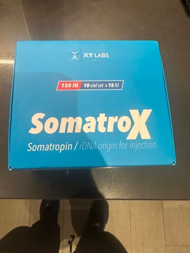 Un cliente muestra la caja azul del producto SomatroX de XT Labs.