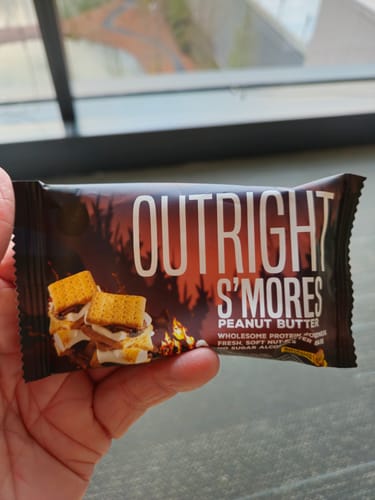 Customer holding a packaged Outright S'mores Peanut Butter Bar.