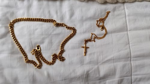 Un cliente muestra su gruesa Cadena Cuban Link Oro sobre una superficie blanca junto a una cadena más delgada.