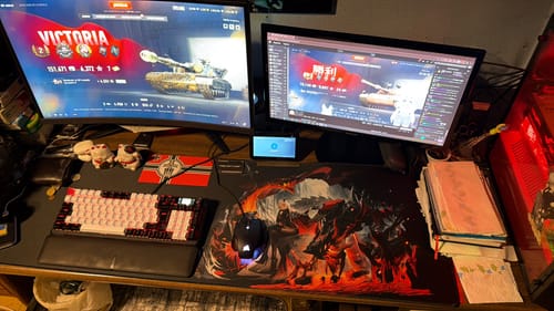 Reviewer's iD Stretch mousepad with a custom fiery graphic, shown on a gaming desk with a keyboard and two monitors.