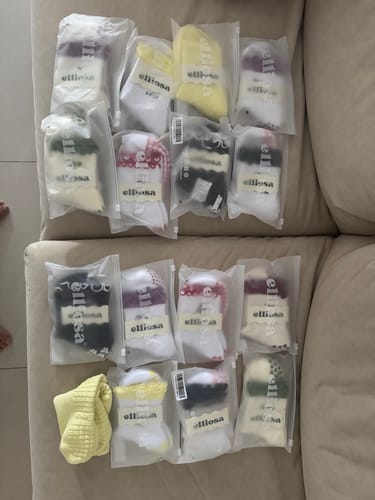 Customer's haul of Elliosa Grip Basics socks in various colors, including Butter Yellow, laid out in packaging on a couch.