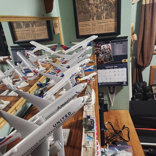 Customer using SKYMARKS SWIVEL STANDS to display a large collection of model airplanes at various angles on a desk.