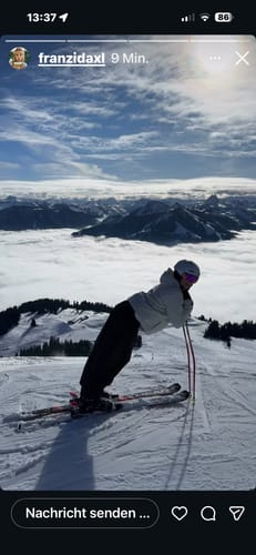 Reviewer posing on a snowy mountaintop in the baggy coffee-colored snow pants.