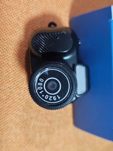 Reviewer's close-up of the black Retro Mini Keychain Camera, showing the 1080p lens and top button.