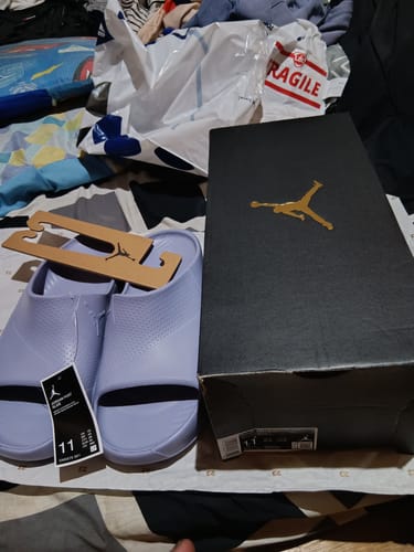 Customer's new light purple Nike Jordan Post Slides displayed next to the black Jordan shoebox.