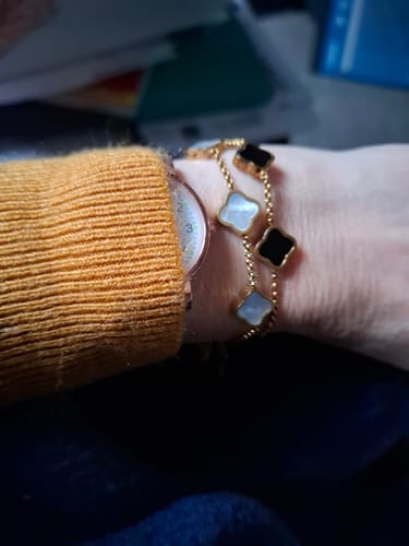 Customer wears the Celine Ten Clover Necklace as a bracelet, showing its gold chain with black and white clover charms.
