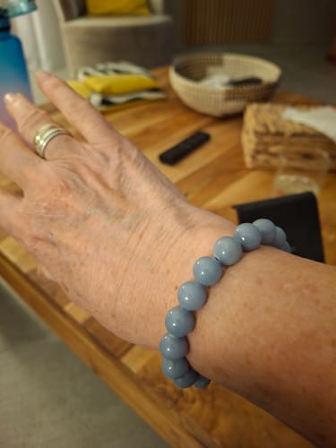 Client montrant les perles bleu clair du bracelet Angélite à son poignet.