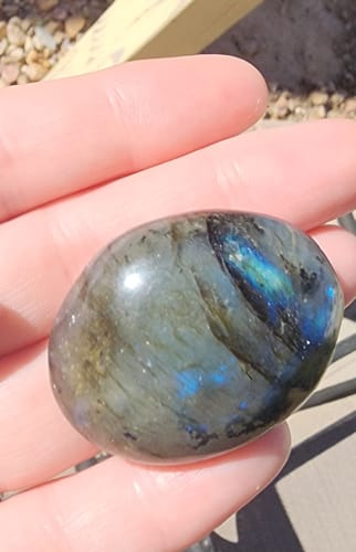 Reviewer holding a smooth, polished labradorite crystal from the VIP Crystal Club in their hand.