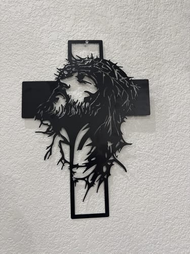 Customer's black metal Crown of Thorns Jesus Cross wall decor hanging on a textured white wall.