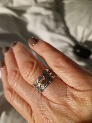 Customer wearing a wide silver-toned ring with a unique design of small fish.