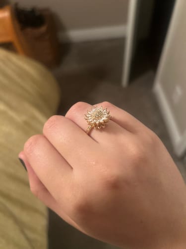 Reviewer wearing the gold, sunflower-shaped You Are My Sunshine Spinning Ring on their finger.