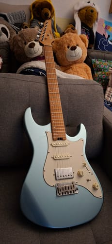 Kunde zeigt seine hellblaue Donner DST-550 E-Gitarre, die auf einem Sofa steht.