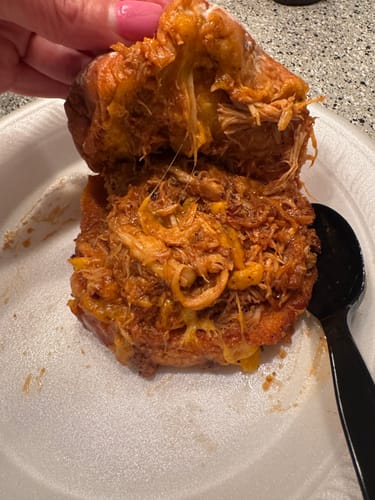 Reviewer holds open the BBQ Chicken Sando, showing the saucy shredded chicken and cheese filling.