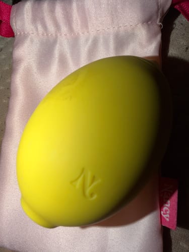 Customer's yellow Lem Clitoral Massager shown with its pink satin storage pouch.