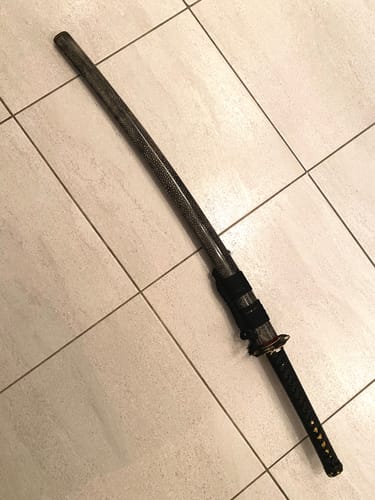 Customer's Kokuryū Katana sword sheathed in its textured black saya, displayed on a tiled floor.