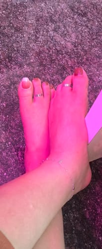 Close-up of a reviewer wearing the Oxidised Silver Alina Toe Rings on both feet under pink lighting.