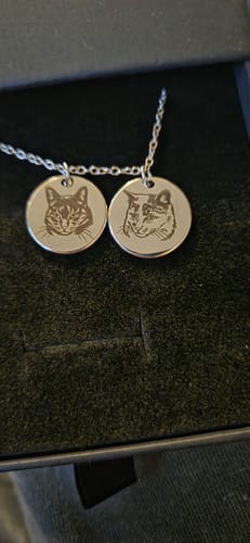 Customer's Pet Portrait Necklace with two round pendants engraved with cat faces, shown inside the gift box.