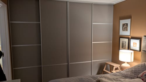 En anmelders skyvedørsgarderobe på et soverom, fornyet med Elliana greige selvklebende tapet.