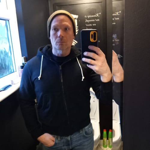 Reviewer taking a mirror selfie while wearing the fitted black Heavyweight Terry Zip-Up Hoodie.