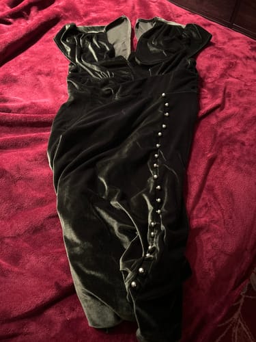 Customer's green velvet dress with pearl buttons and cap sleeves laid on a red blanket.