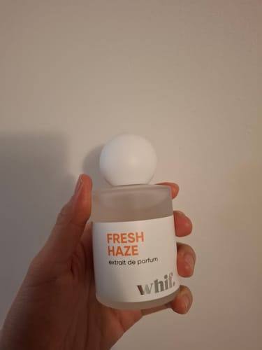 Reviewer holding the frosted glass bottle of Fresh Haze perfume in their hand.