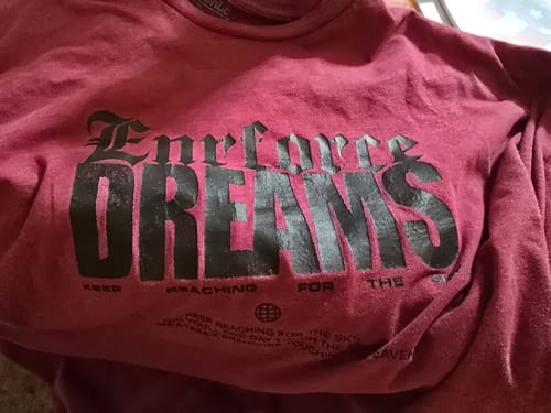 Customer showing a different maroon t-shirt from a previous purchase with 'Enrforce DREAMS' text.