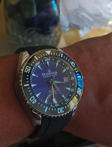 Customer wearing the Oceaneva 6000m watch, showing its purple dial and glowing blue lume on the markers.