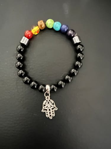 Reviewer's chakra bracelet with colorful crystal beads, shiny black beads, and a silver Hamsa charm.