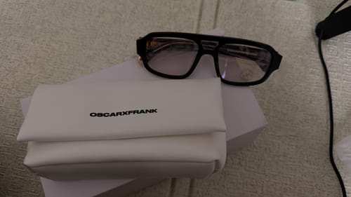 Customer's MAKATI gloss black sunglasses with purple photochromic lenses resting on their white branded case.