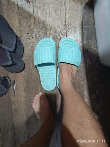 Customer's personal view, wearing one aqua adidas Adissage slide on a wooden floor.