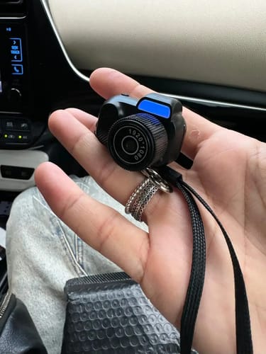 Customer holding the black Retro Mini Keychain Camera in their palm, showing its compact size and bright blue light.
