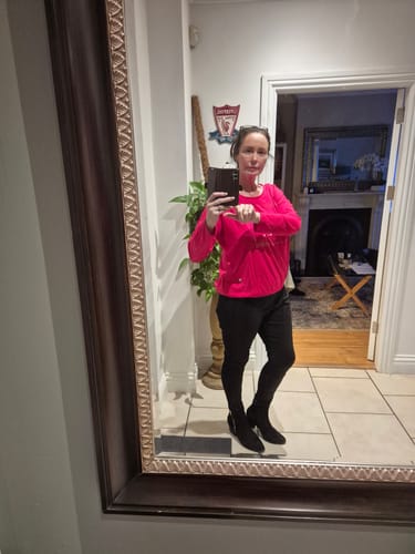 Customer taking a mirror selfie showing the comfortable fit of the bright pink Spring Ruby Glossy Night Top.
