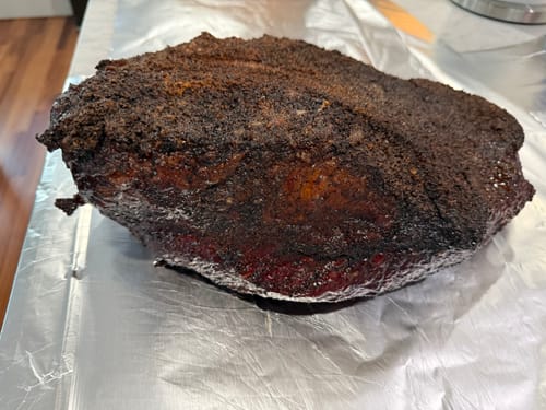 Reviewer's cooked USDA Prime Brisket with a dark, seasoned crust resting on aluminum foil.