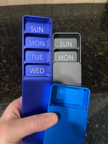 Customer holding sturdy, colorful metal pill cases.