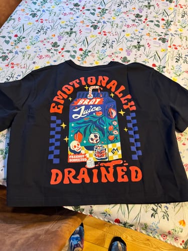 Customer's black Emotionally Drained T-Shirt laid flat, showing the colorful 'Brat Juice' graphic on the back.