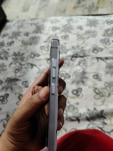 Reviewer's hand holding a phone in the Anti Yellow Clear Case, showing the side view and aluminum buttons.