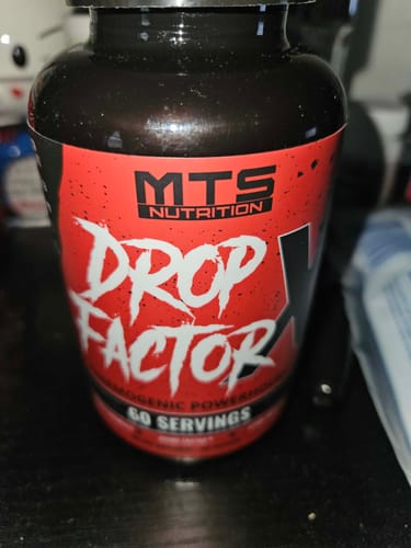 Customer's bottle of Drop Factor X, showing its red and black label on a dark surface.