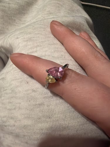 A customer's hand wearing the Leesha Birthstone Ring with a large pink and smaller yellow stone.