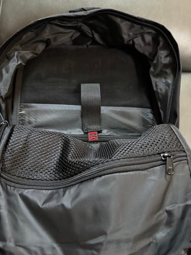 Close-up of the reviewer's open RSVLTS Black Backpack, showing the interior laptop compartment and mesh pocket.