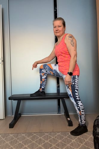 Arvostelija esittelee mustia Vaistoa Tahto -kenkiään, toinen jalka lepää treenipenkillä.