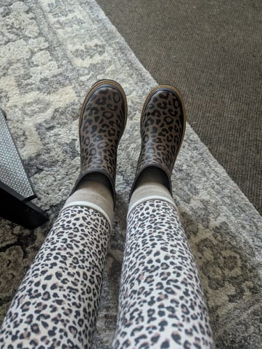 A reviewer's top-down view of their Corky's Leopard Drip Boots paired with leopard print leggings.
