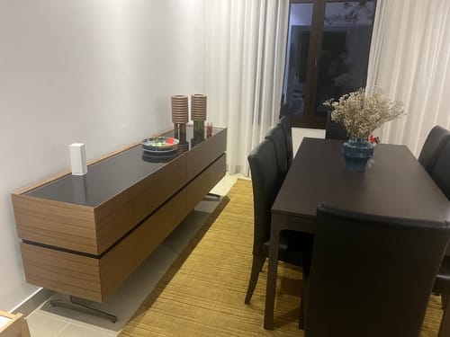 Customer's Icona Sideboard with a wood finish and black top, placed in a dining room next to a table.