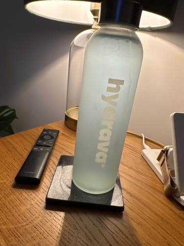 Customer's frosted Hydrava water bottle containing their electrolyte drink, on a bedside table.