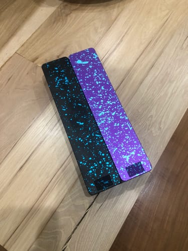 Customer's two Weekly AM-PM Vitamin XL Cases, one purple and one black, with a colorful splatter paint design.