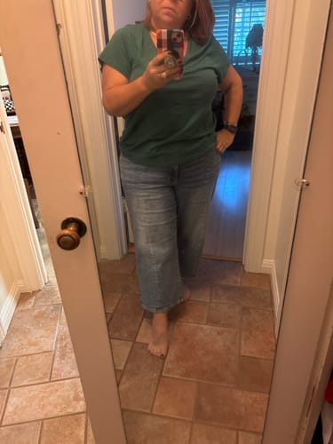 Reviewer in a mirror selfie showing the fit of the light wash Judy Blue wide leg crop jeans.